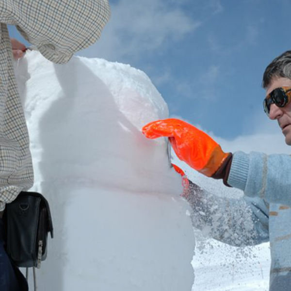 Mann schnitzt eine Skulptur aus Schnee im Iglu-Dorf