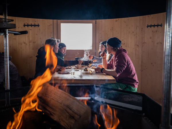 Eine Gruppe geniesst ein Käsefondue in der Kota im Iglu-Dorf Davos Klosters