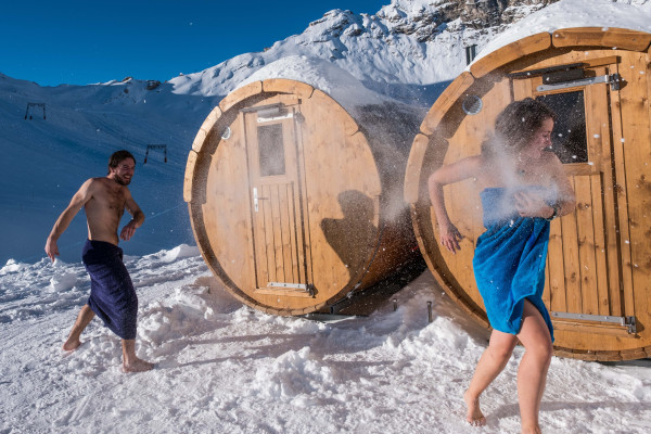 Ein Paar schiesst Schneebälle vor der Fasssauna im Iglu-Dorf